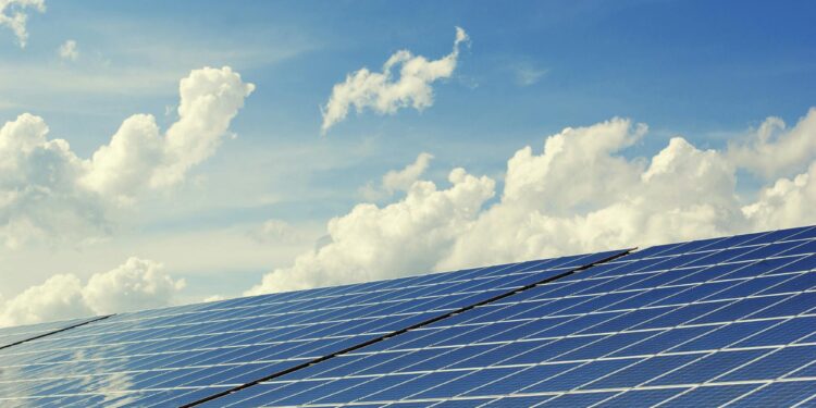 Sleek modern solar panels under a vibrant blue sky with clouds, symbolizing clean energy.