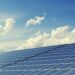 Sleek modern solar panels under a vibrant blue sky with clouds, symbolizing clean energy.